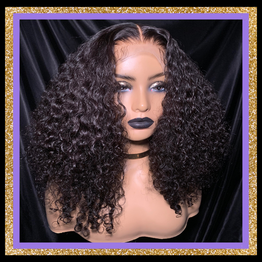 A mannequin head displaying a wig with curly hair, wearing a comb at the nape and an adjustable elastic band.